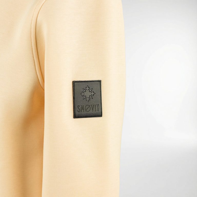 Nahaufnahme des einzigartigen SNØVIT Lederpatches auf dem beigen Sweatshirt Phantom Nebula.