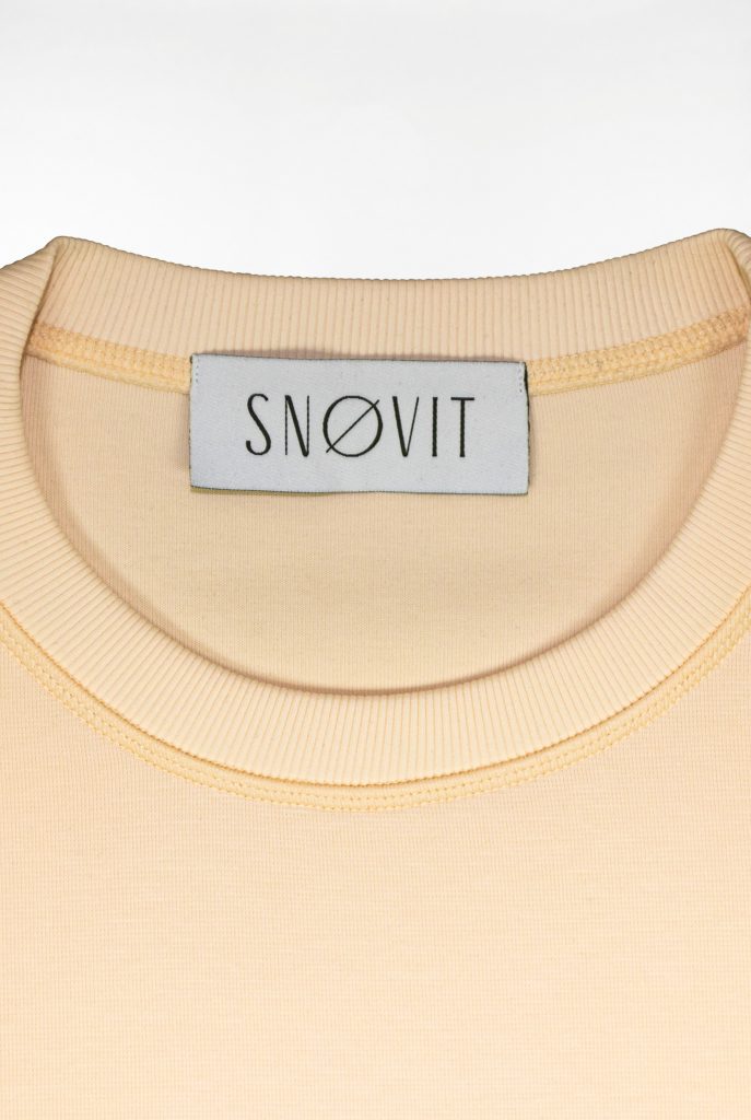 Nahaufnahme des SNØVIT Brand Tags im beigen Sweatshirt Phantom Nebula – sichtbar auf der Innenseite.