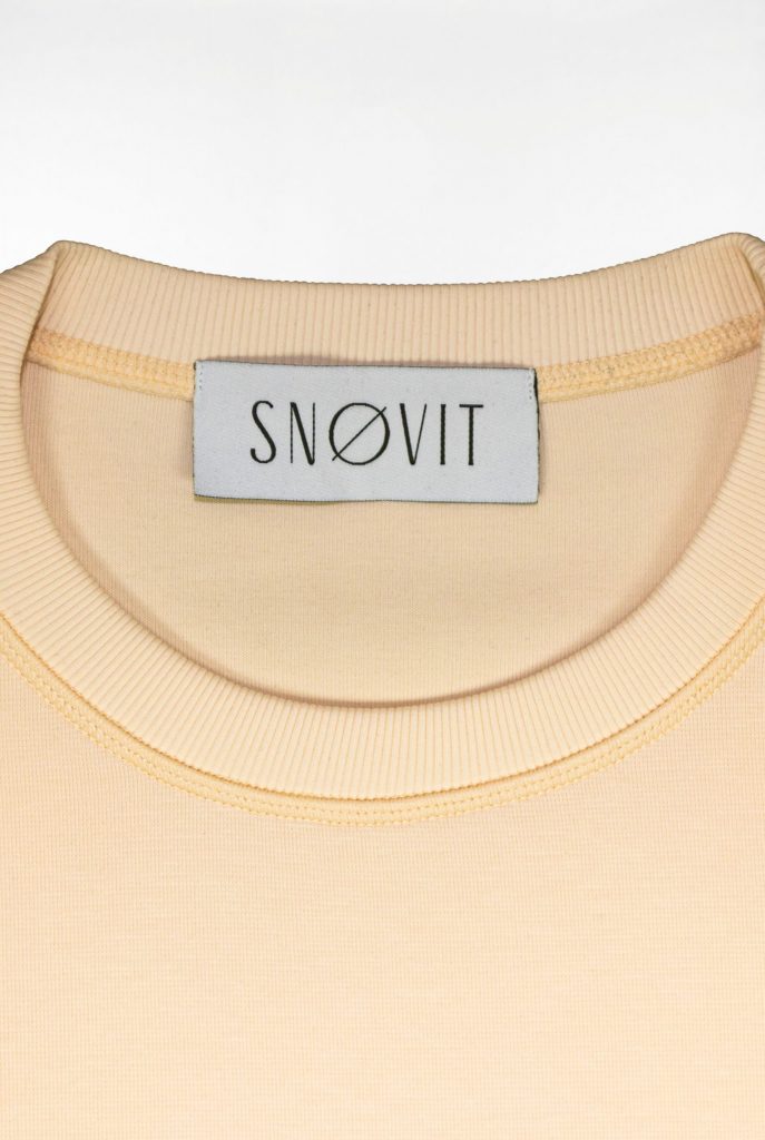 Nahaufnahme des SNØVIT Brand Tags im beigen Sweatshirt Phantom Nebula – sichtbar auf der Innenseite.