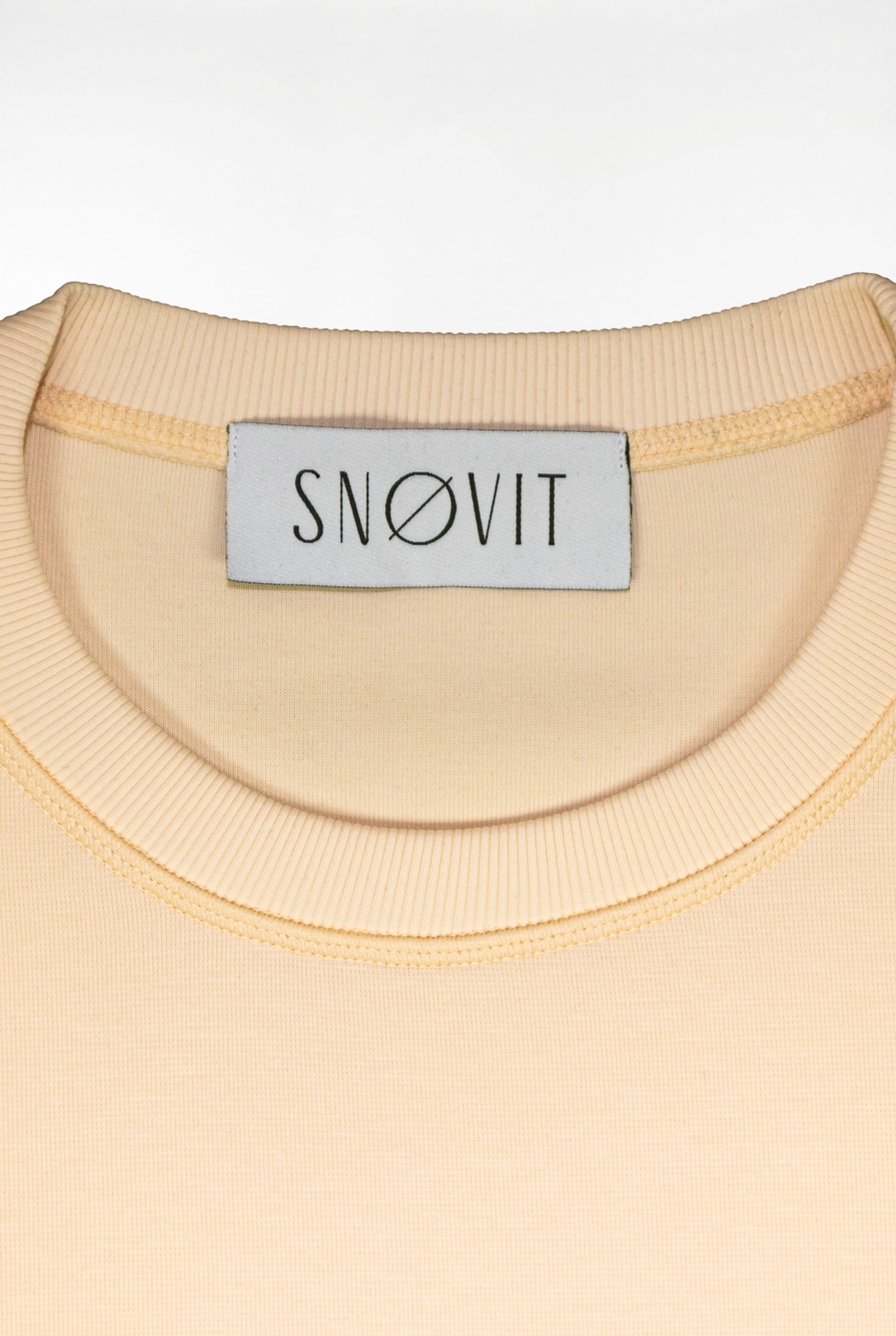 Nahaufnahme des SNØVIT Brand Tags im beigen Sweatshirt Phantom Nebula – sichtbar auf der Innenseite.