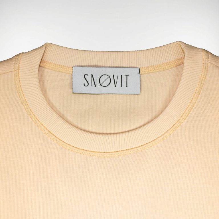 Nahaufnahme des SNØVIT Brand Tags im beigen Sweatshirt Phantom Nebula – sichtbar auf der Innenseite.