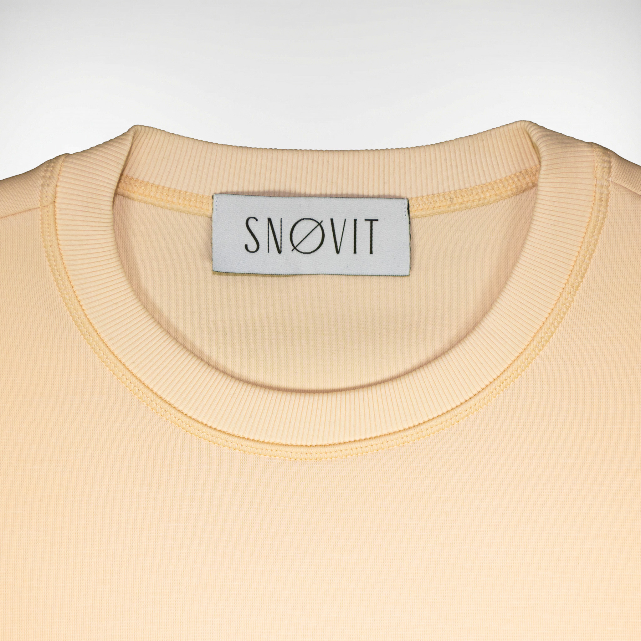 Nahaufnahme des SNØVIT Brand Tags im beigen Sweatshirt Phantom Nebula – sichtbar auf der Innenseite.