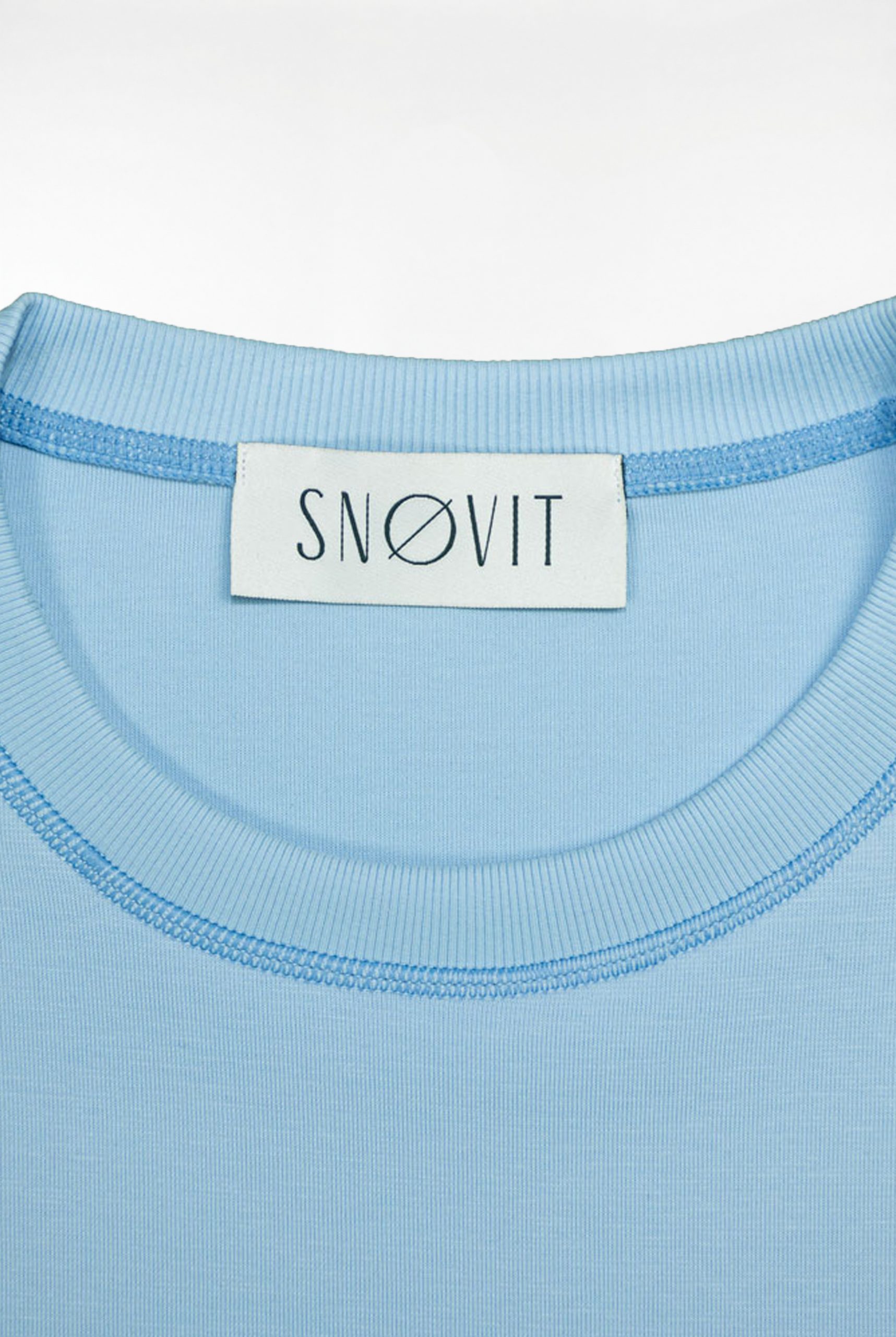 Nahaufnahme des blauen SNØVIT Brand-Tags im Deep Horizon Sweatshirt, Details des Stoffes sichtbar.