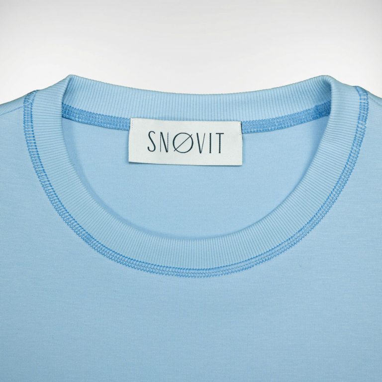 Nahaufnahme des blauen SNØVIT Brand-Tags im Deep Horizon Sweatshirt, Details des Stoffes sichtbar.