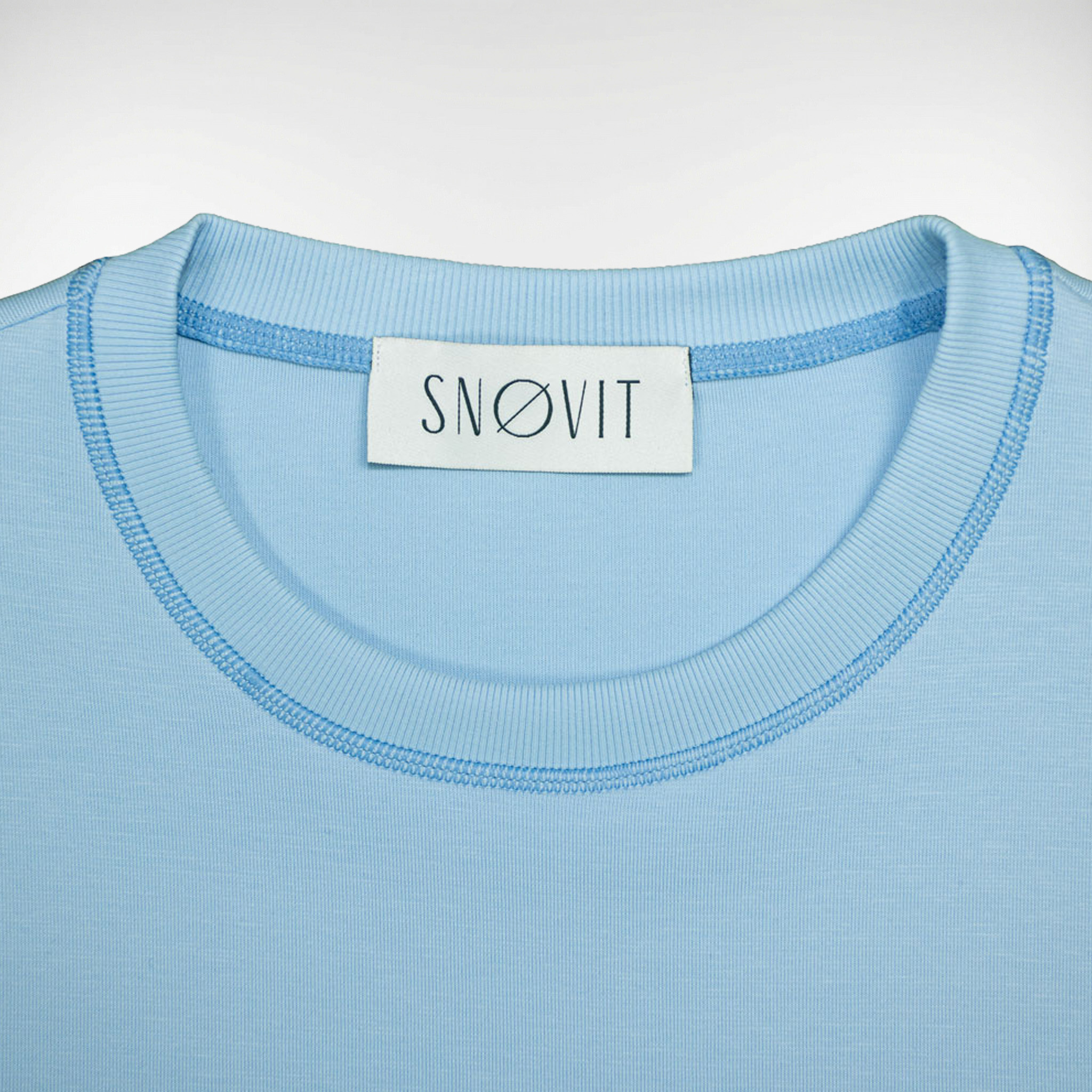 Nahaufnahme des blauen SNØVIT Brand-Tags im Deep Horizon Sweatshirt, Details des Stoffes sichtbar.