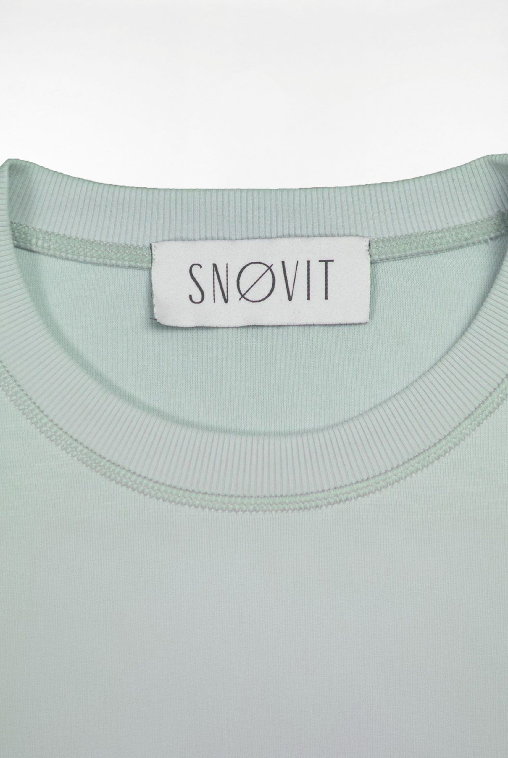 Nahaufnahme des SNØVIT Brand Tags im hellgrauen Arctic La Goone Sweatshirt.