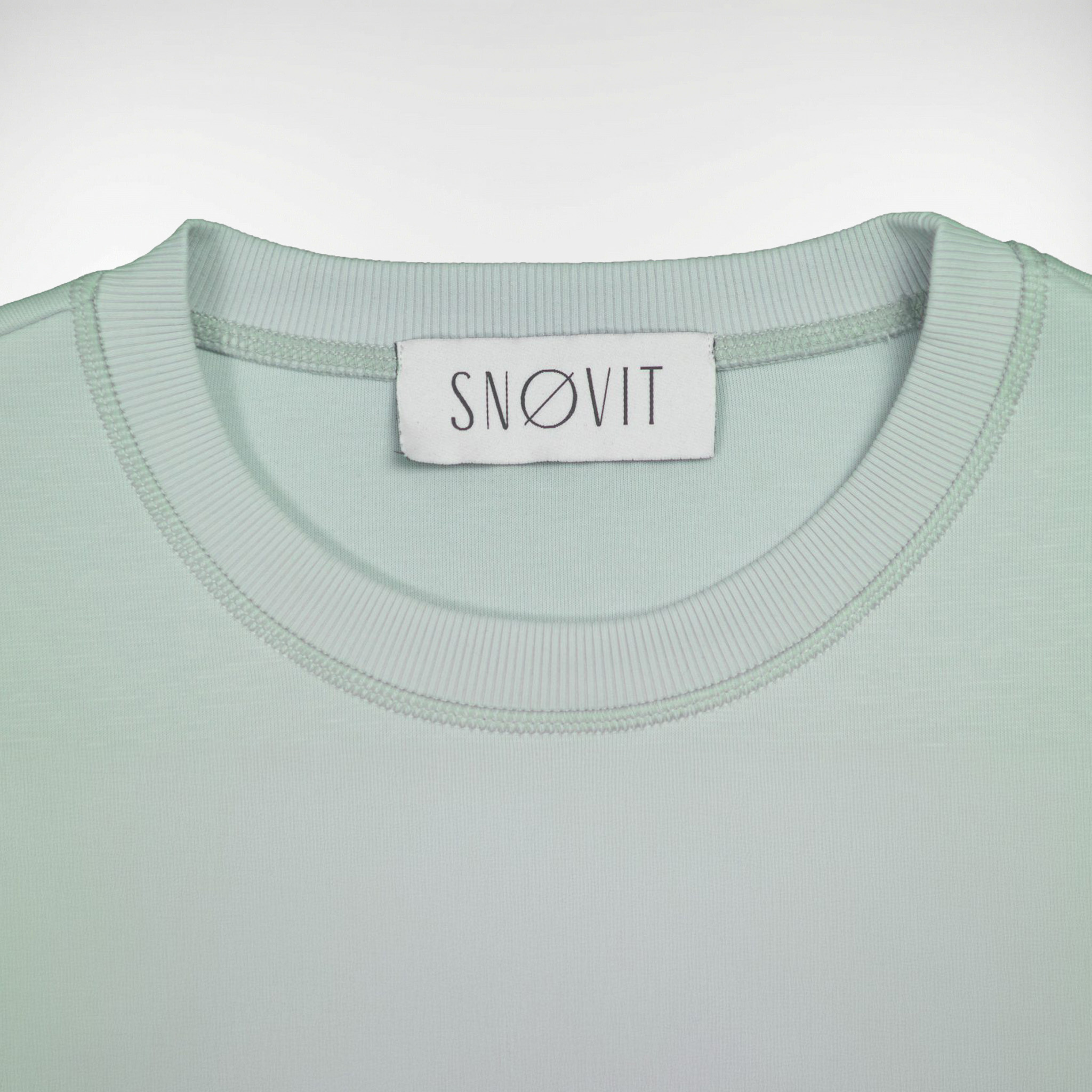 Nahaufnahme des SNØVIT Brand Tags im hellgrauen Arctic La Goone Sweatshirt.