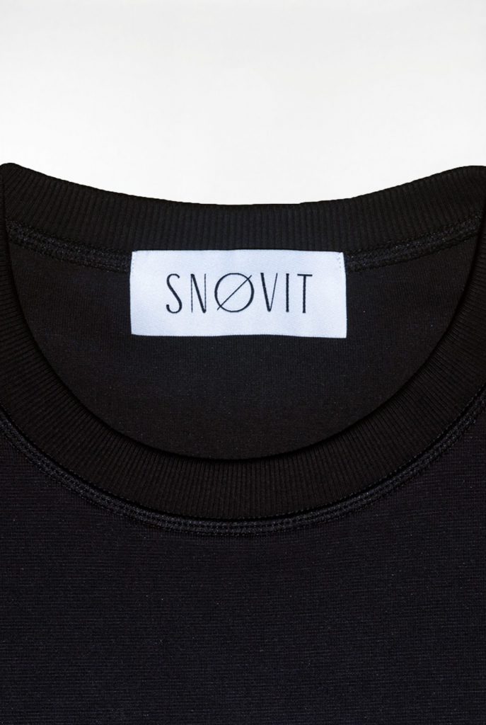 Nahaufnahme des schwarzen SNØVIT Brand-Tags im Midnight Cøre Sweatshirt, Details des Stoffes sichtbar.