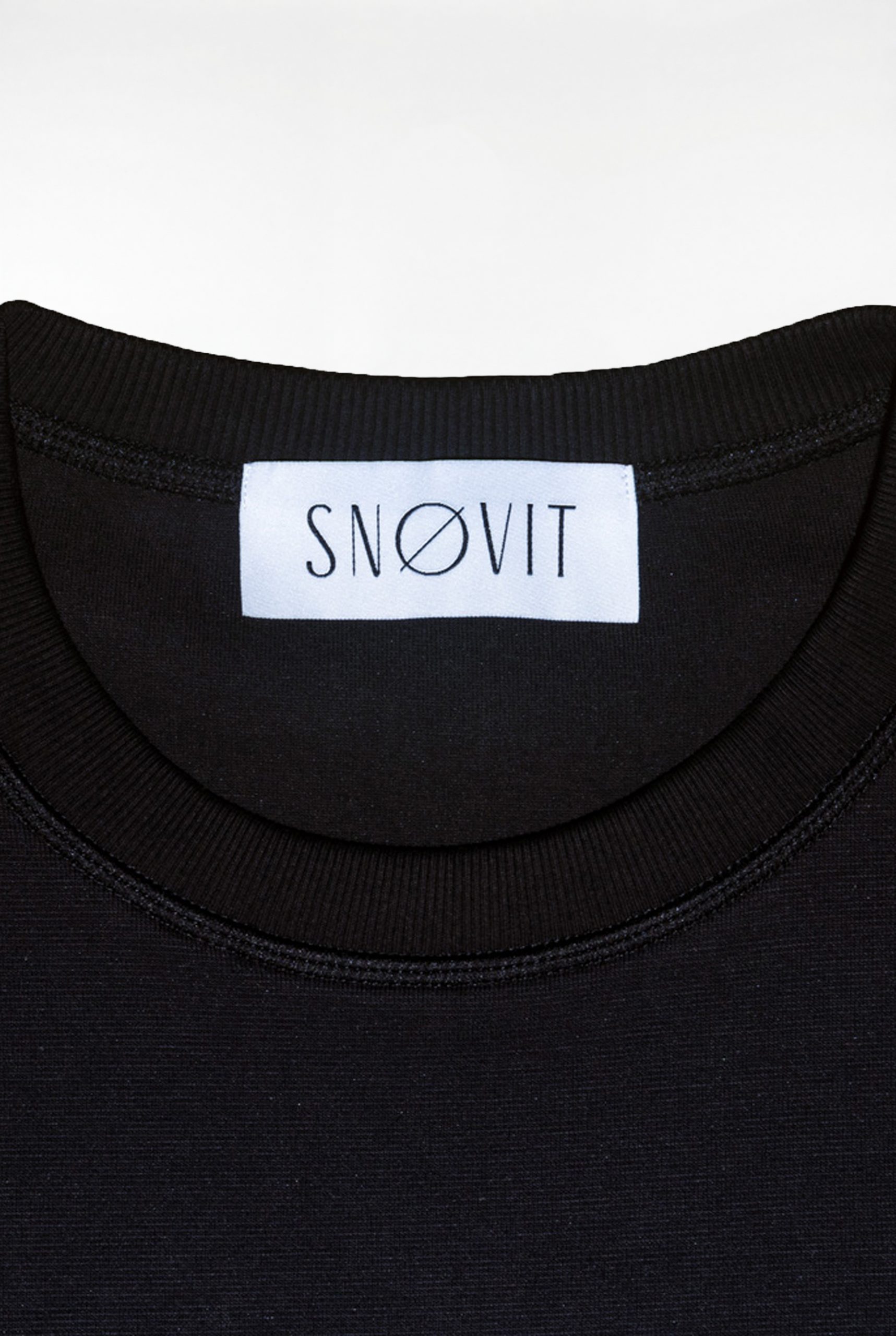 Nahaufnahme des schwarzen SNØVIT Brand-Tags im Midnight Cøre Sweatshirt, Details des Stoffes sichtbar.