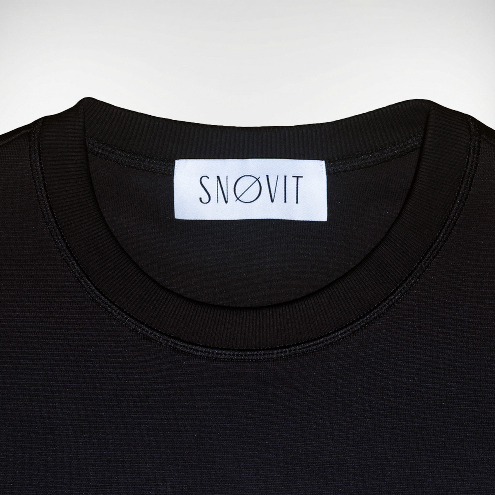 Nahaufnahme des schwarzen SNØVIT Brand-Tags im Midnight Cøre Sweatshirt, Details des Stoffes sichtbar.