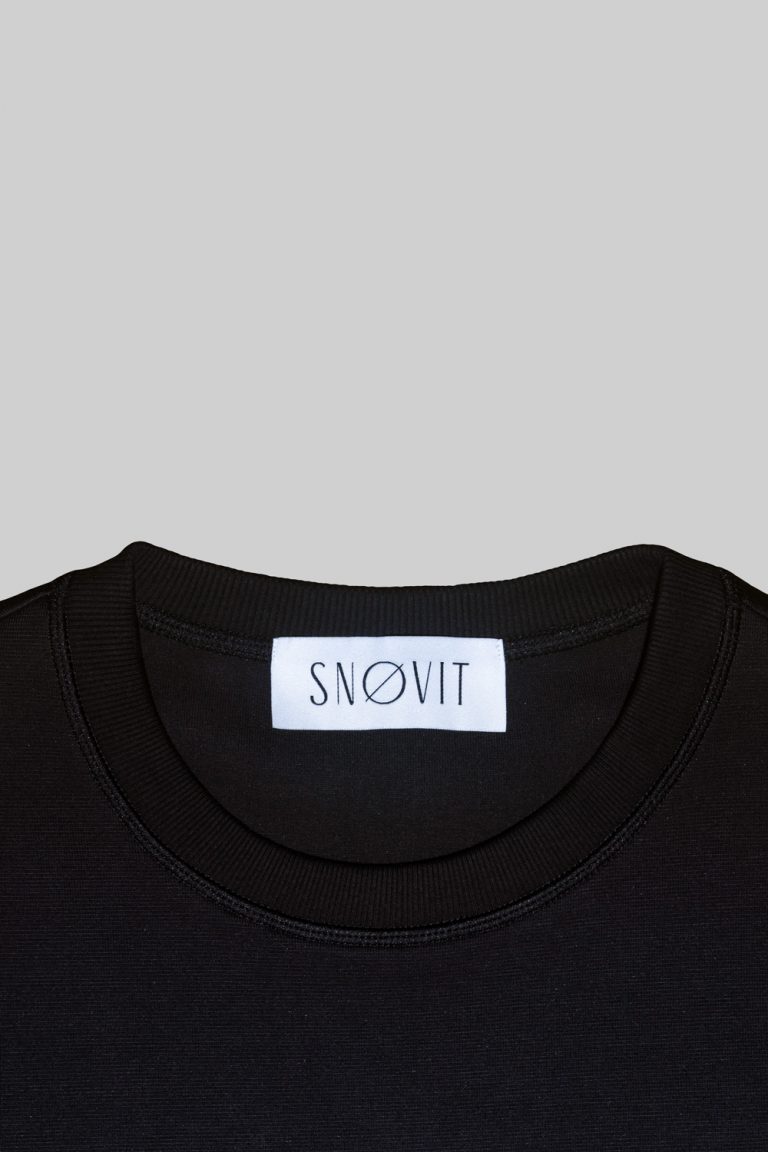 Nahaufnahme des schwarzen SNØVIT Brand-Tags im Midnight Cøre Sweatshirt, Details des Stoffes sichtbar.