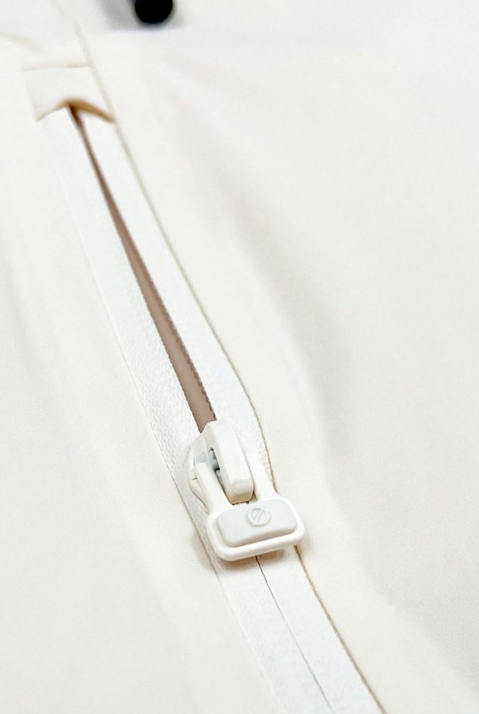 Nahaufnahme des Ø-Zippers als Zughilfe an der beige SNØVIT Moonlighter X Outdoor-Jacke für einfaches Öffnen und Schließen.