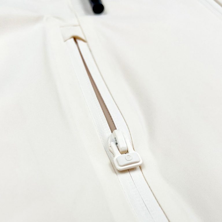 Nahaufnahme des Ø-Zippers als Zughilfe an der beige SNØVIT Moonlighter X Outdoor-Jacke für einfaches Öffnen und Schließen.