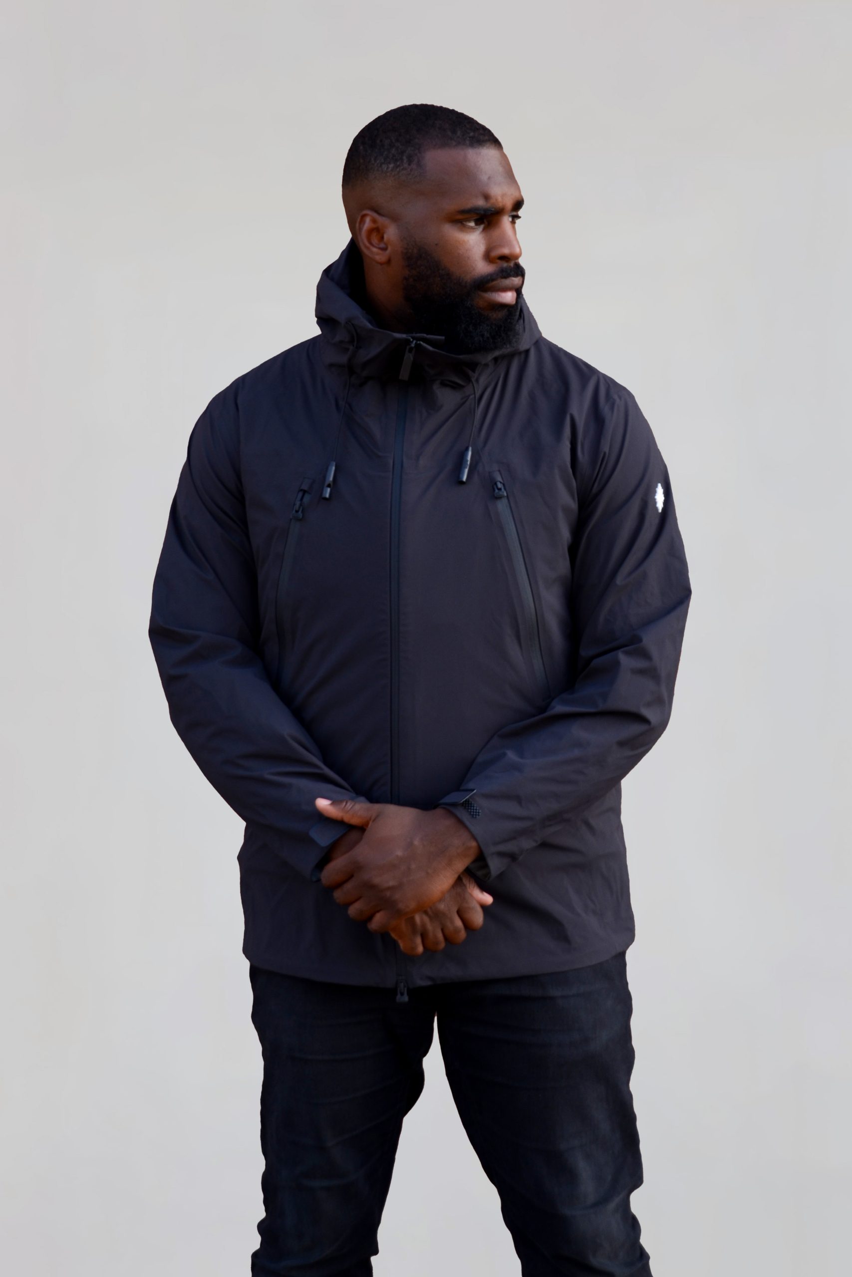 Model trägt schwarze Nithya nova x jacke seitlicher Stand. Arme in Mitte verschrenkt.