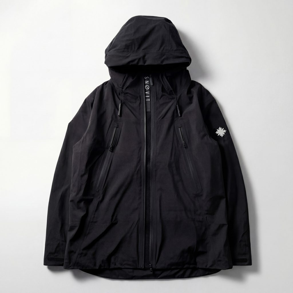 Vorderseite der schwarzen SNØVIT Nithya Nøva X Outdoor-Jacke mit zwei Belüftungs-Zippern und sichtbarem SNØVIT-Logo.