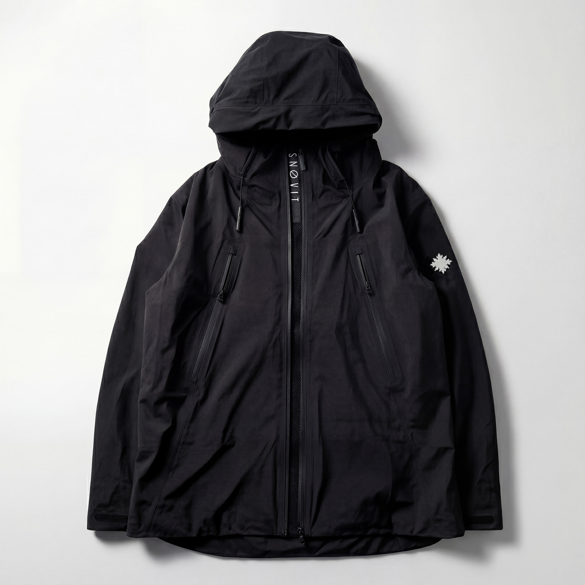 Vorderseite der schwarzen SNØVIT Nithya Nøva X Outdoor-Jacke mit zwei Belüftungs-Zippern und sichtbarem SNØVIT-Logo.