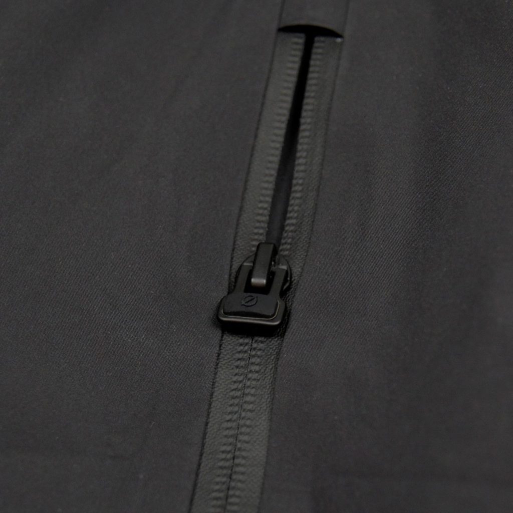 Detailaufnahme des hochwertigen Zipper-Accessoires mit ergonomischem Ø-Öffner an der schwarzen SNØVIT Nithya Nøva X Outdoor-Jacke.