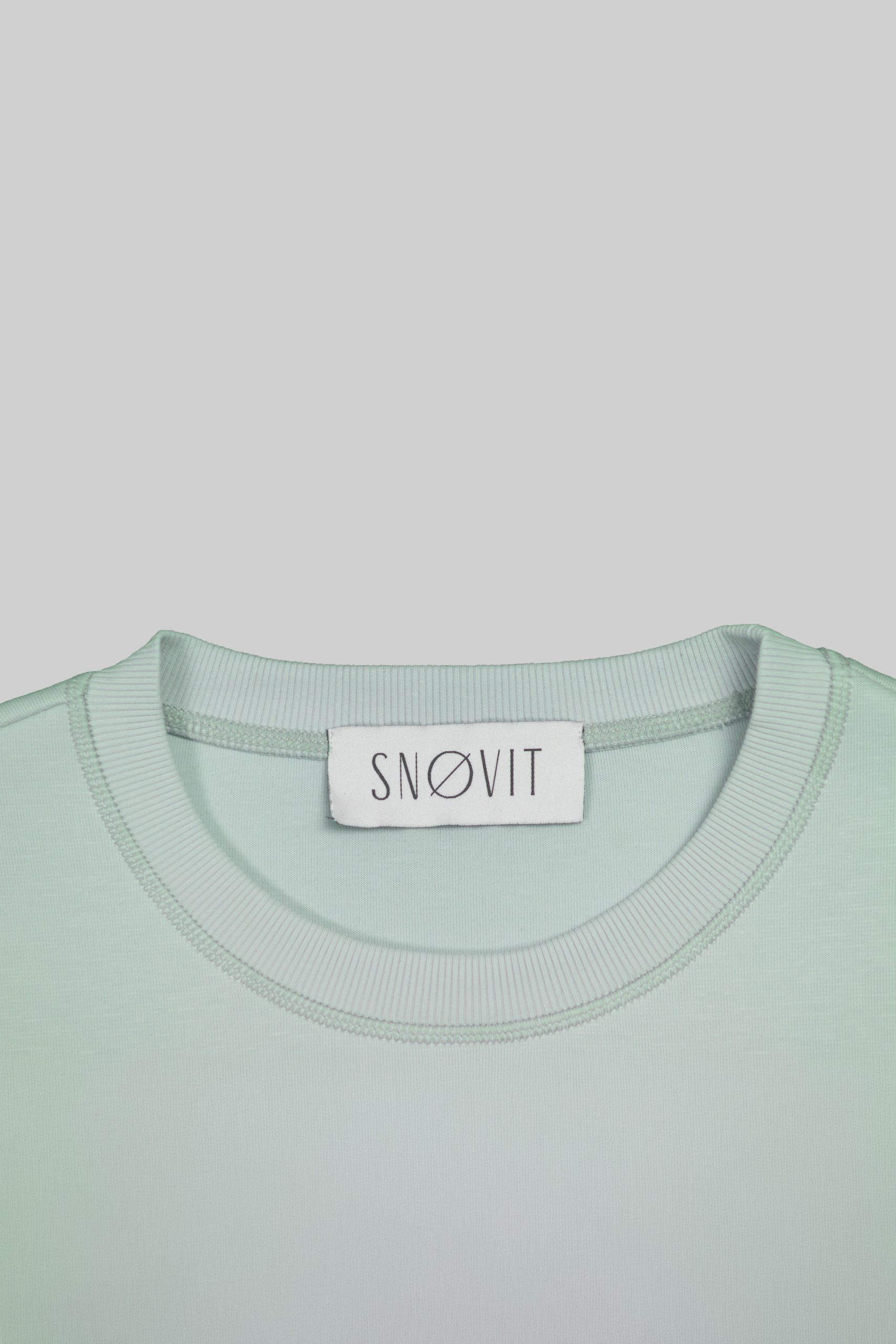 Nahaufnahme des SNØVIT Brand Tags im hellgrauen Arctic La Goone Sweatshirt.