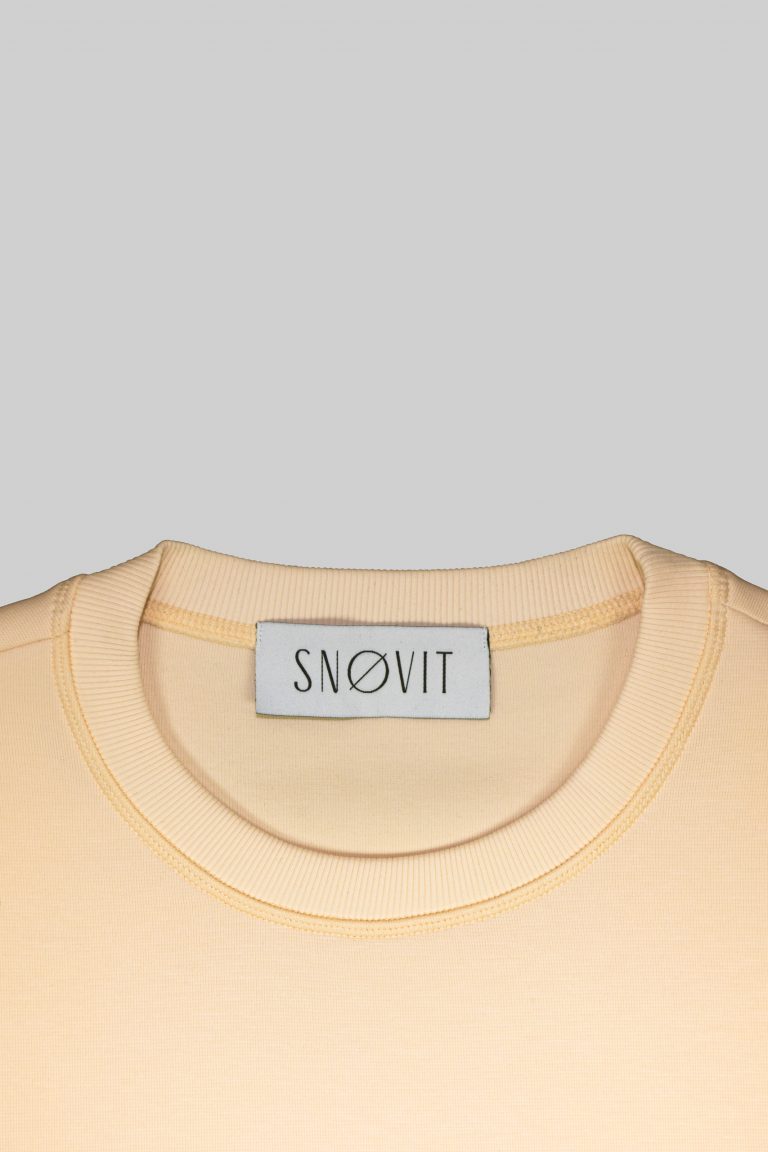 Nahaufnahme des SNØVIT Brand Tags im beigen Sweatshirt Phantom Nebula – sichtbar auf der Innenseite.