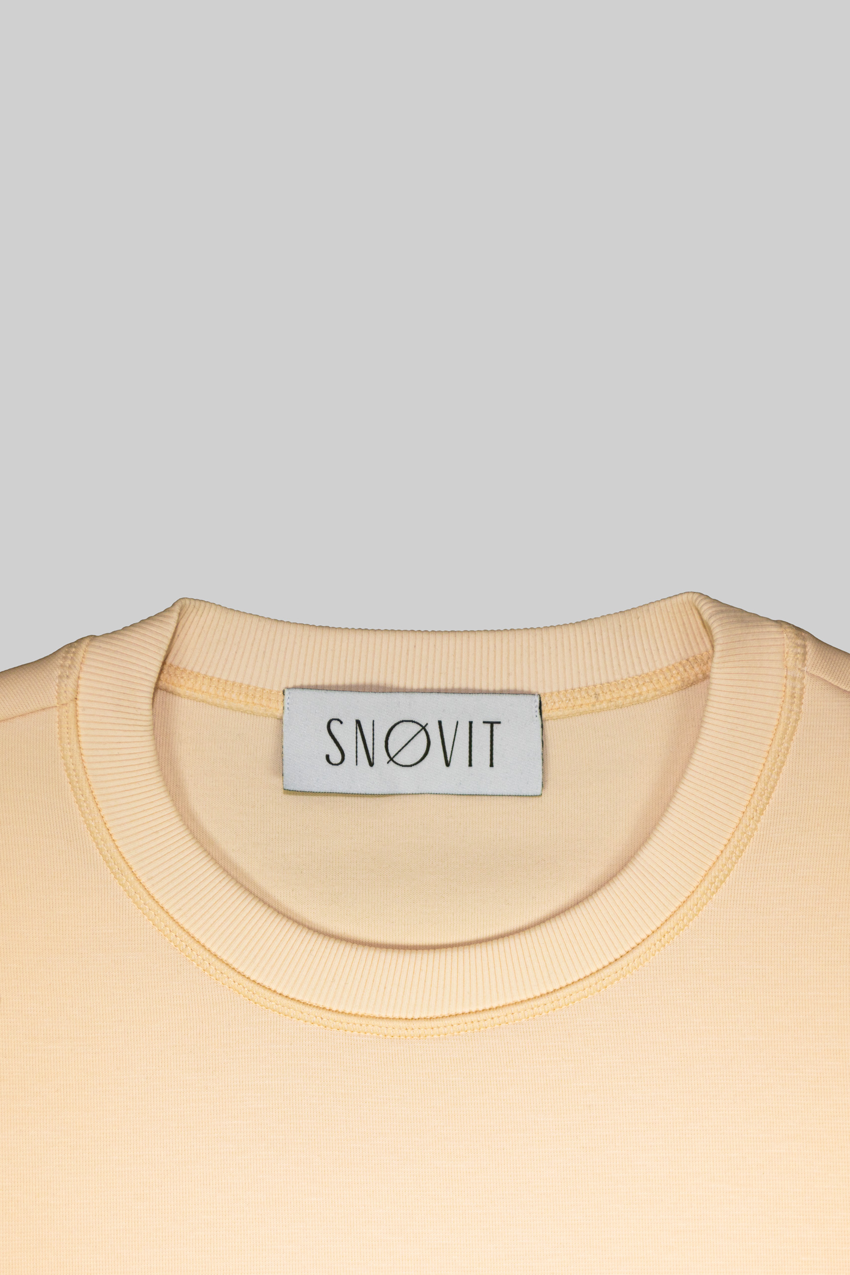 Nahaufnahme des SNØVIT Brand Tags im beigen Sweatshirt Phantom Nebula – sichtbar auf der Innenseite.