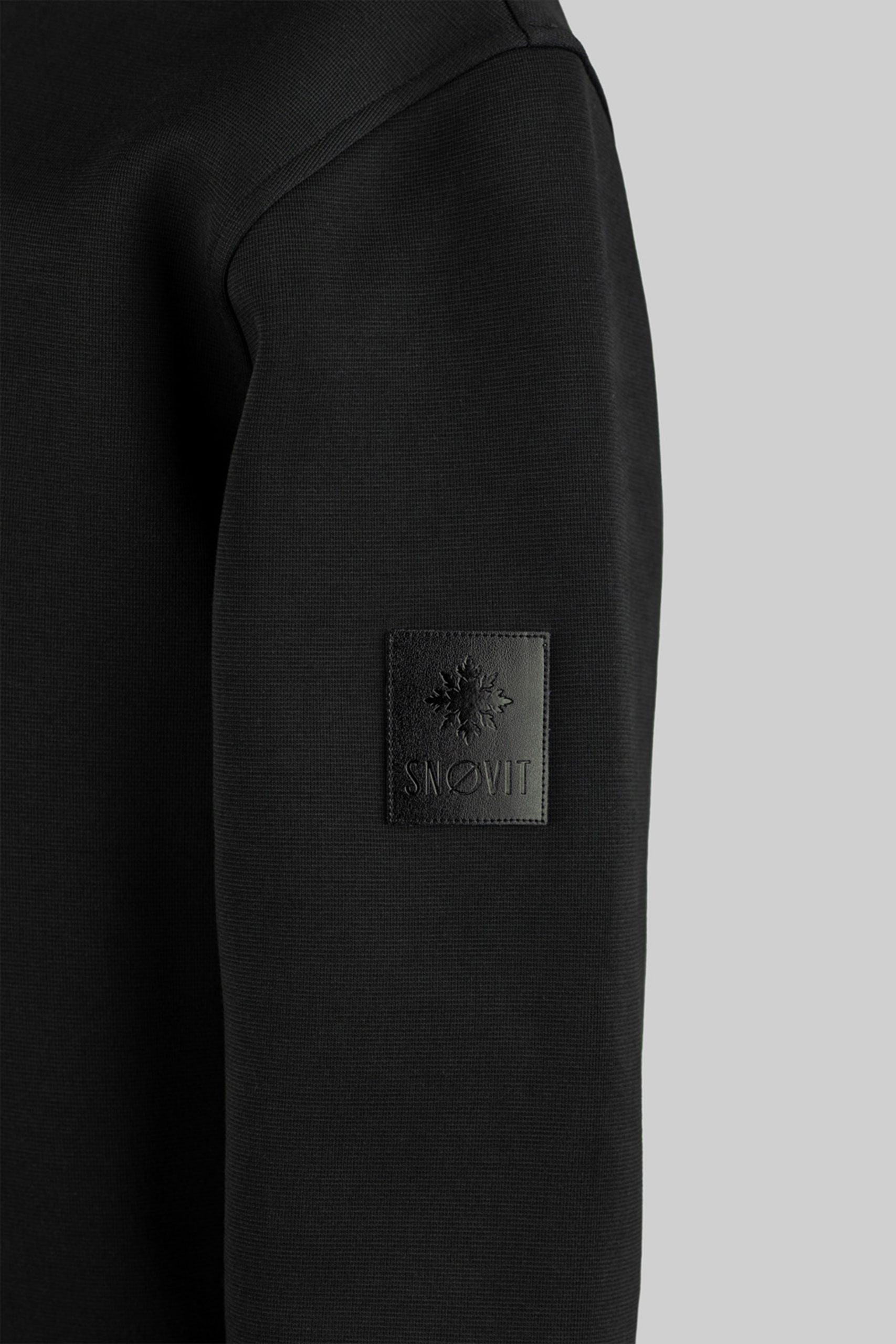 Nahaufnahme des schwarzen SNØVIT Midnight Cøre Sweatshirts mit einzigartigem Lederpatch.