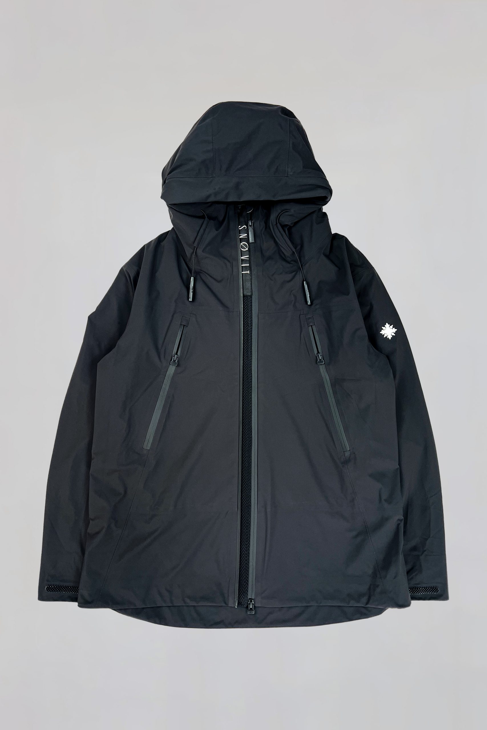 Vorderseite der schwarzen SNØVIT Nithya Nøva X Outdoor-Jacke mit zwei Belüftungs-Zippern und sichtbarem SNØVIT-Logo.