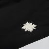 Nahaufnahme des hochwertigen weißen Schneeflocken-Rubber-Logos auf der schwarzen Nithya Nøva X Outdoor-Jacke von SNØVIT.