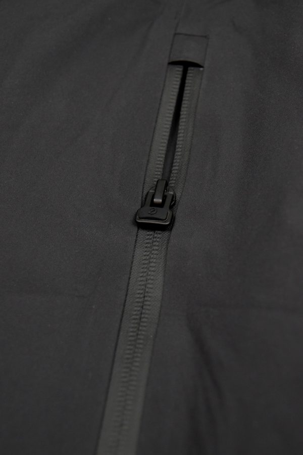 Detailaufnahme des hochwertigen Zipper-Accessoires mit ergonomischem Ø-Öffner an der schwarzen SNØVIT Nithya Nøva X Outdoor-Jacke.
