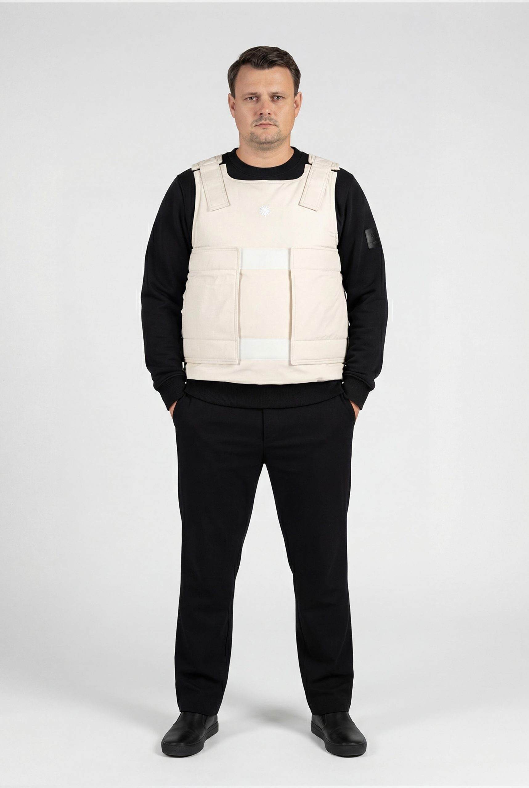 Model trägt beige Defenx pro Weste mit VPAM zertifizierten Panelen innen und schaut geradeaus.