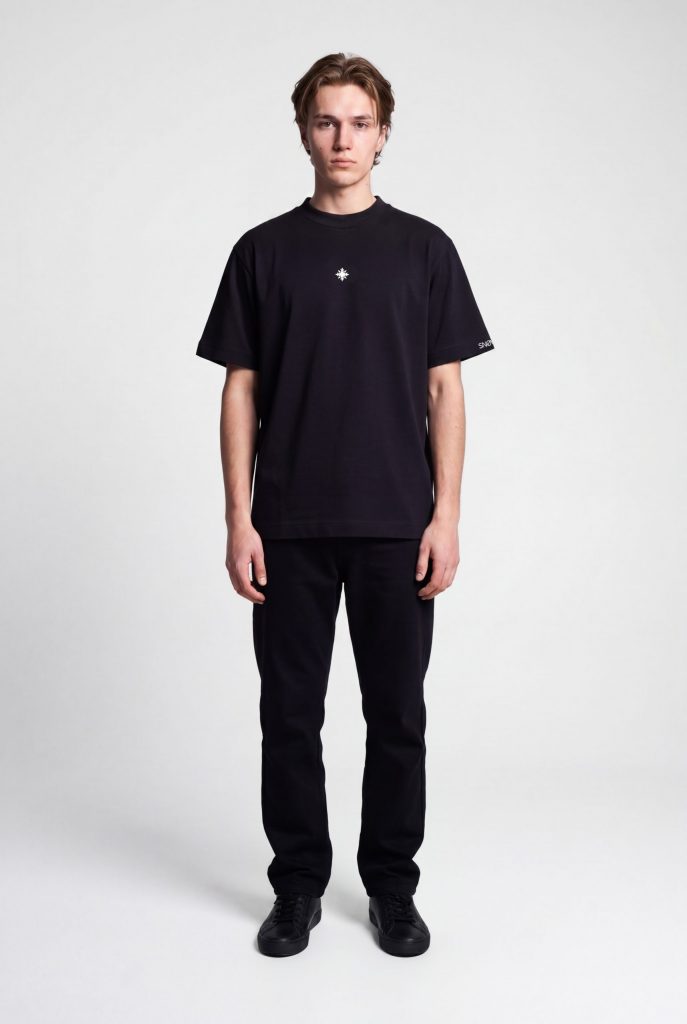 Model trägt schwarzes SNØVIT Eclipse T-Shirt im Produktstudio – minimalistisches Design, 100 % Baumwolle, moderne Passform, zeitloses Basic.
