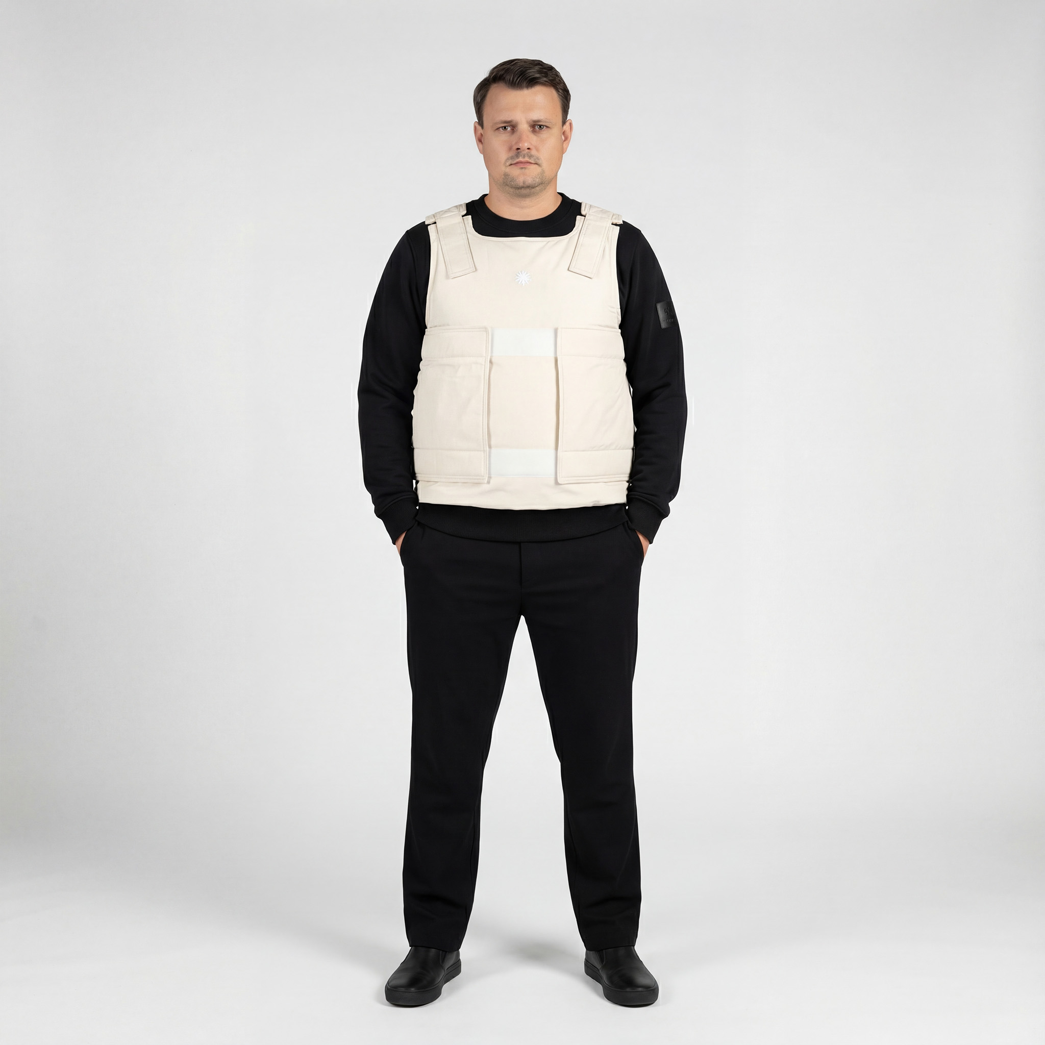 Model trägt beige Defenx pro Weste mit VPAM zertifizierten Panelen innen und schaut geradeaus.